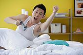 Man sitting in bed, holding video game remote control, arms ... Man sitting in bed, holding video game remote control, arms ...